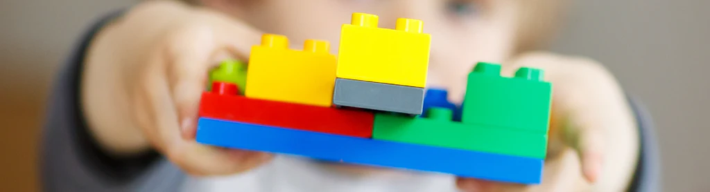 A child building a story scene with colorful blocks and an open book.
